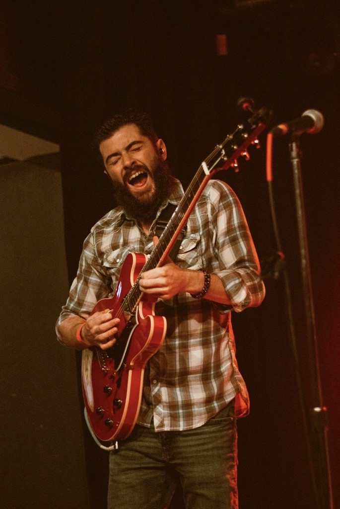 Mike Martin playing guitar under stage lighting