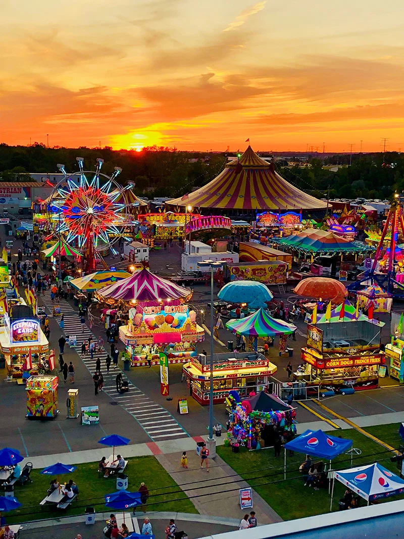 Michigan State Fair midway at sunset with ferris wheel and carnival tents